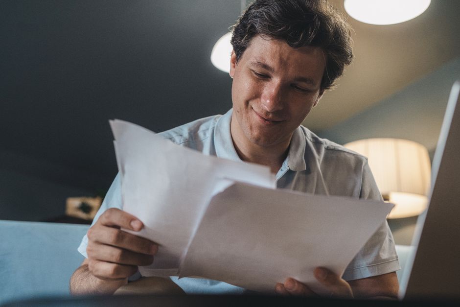 Personne consultant calmement ses documents à son bureau, ordinateur ouvert